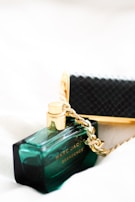 A luxurious perfume bottle with gold accents linked to a golden chain, placed on a soft, neutral background. The bottle is labeled with the word 'Decadence' in elegant typography.