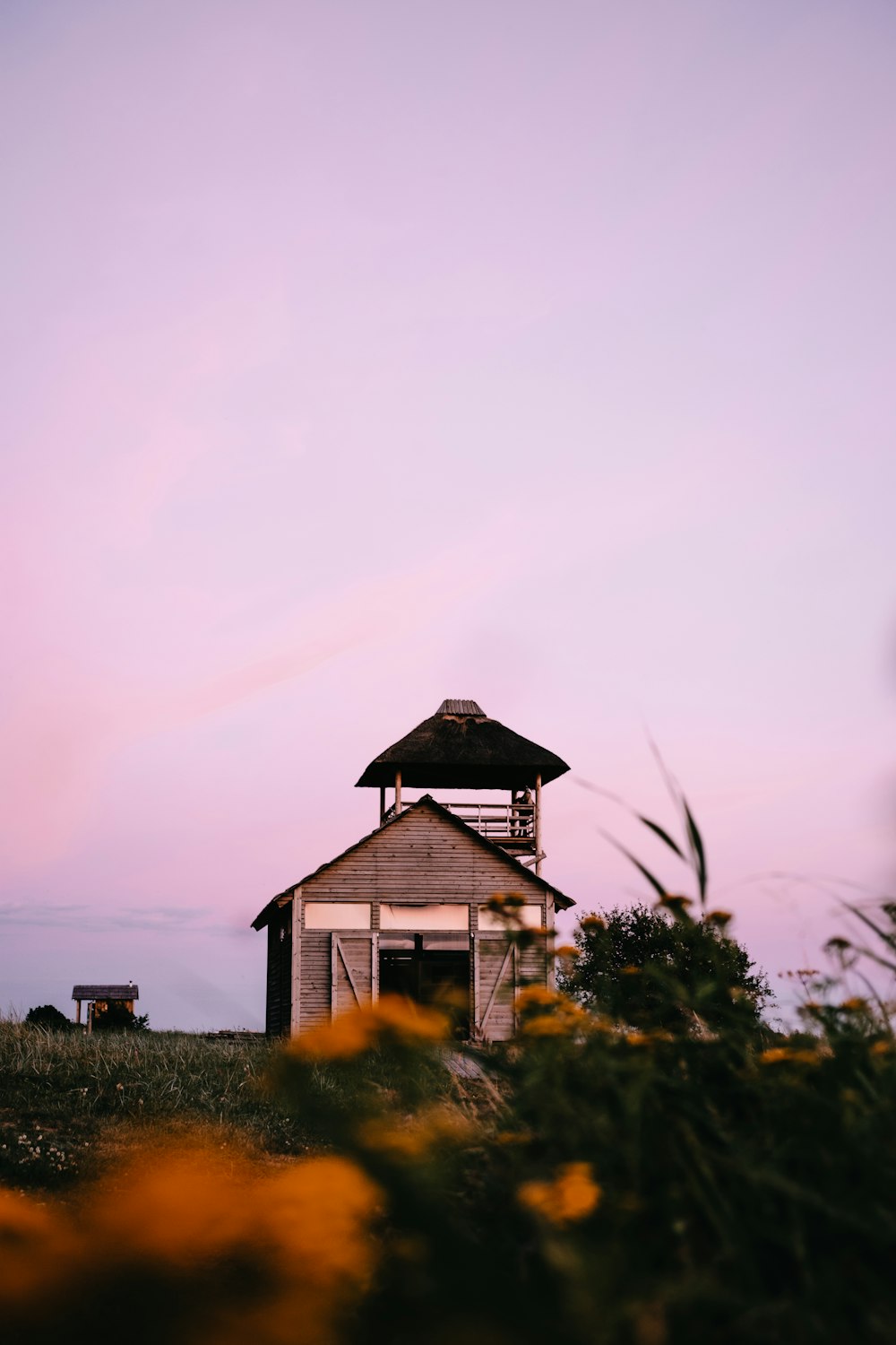 maison en bois marron sur un champ d’herbe verte sous un ciel blanc pendant la journée
