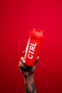 person holding red and white nescafe container