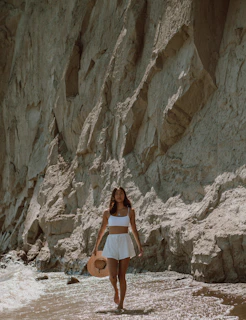 Woman wearing a stylish swimsuit walking along a rocky shoreline