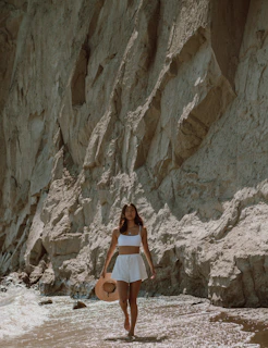 Woman wearing a stylish swimsuit walking along a rocky shoreline