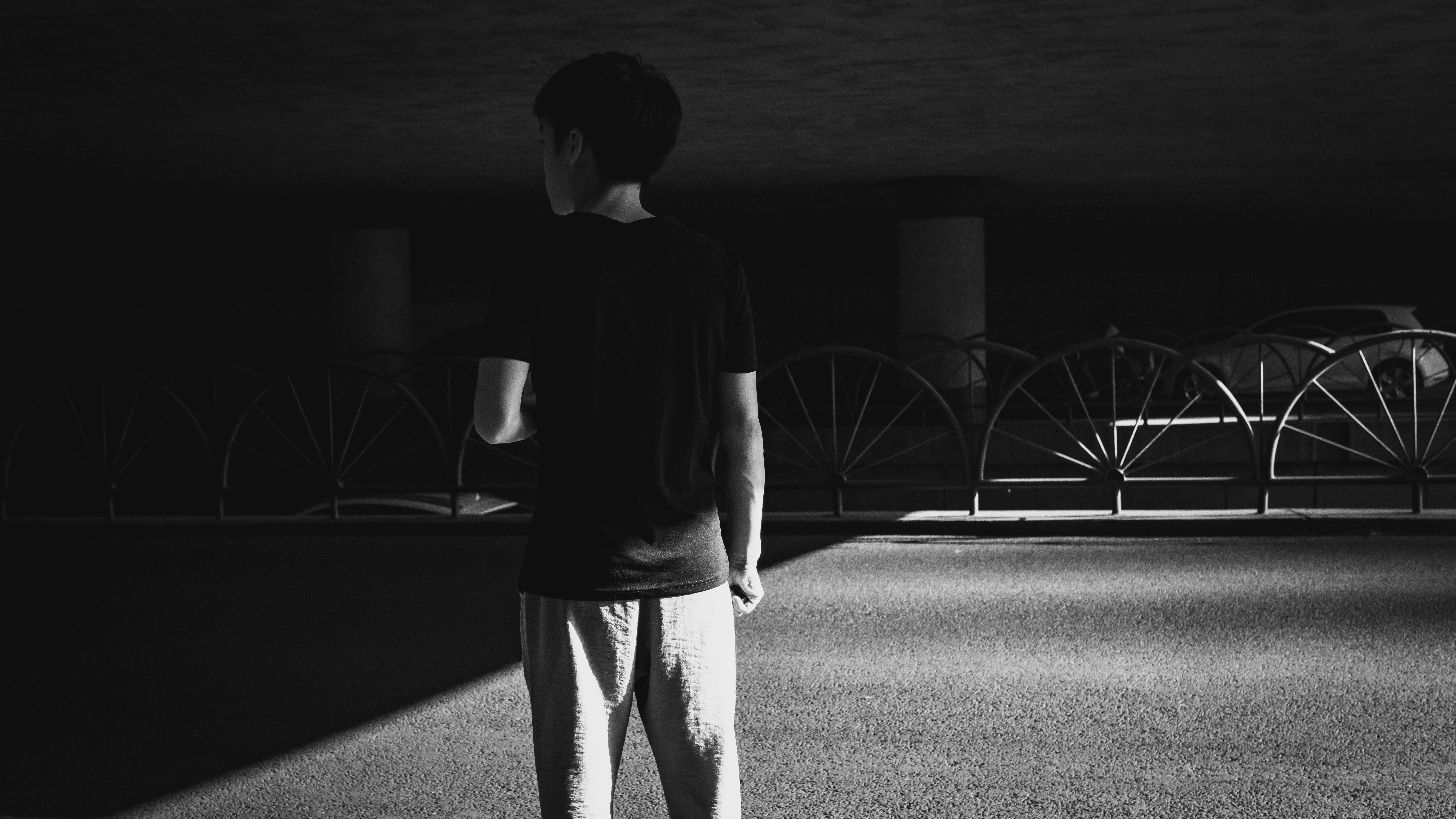 man in black crew neck t-shirt and gray pants standing on black and white photography