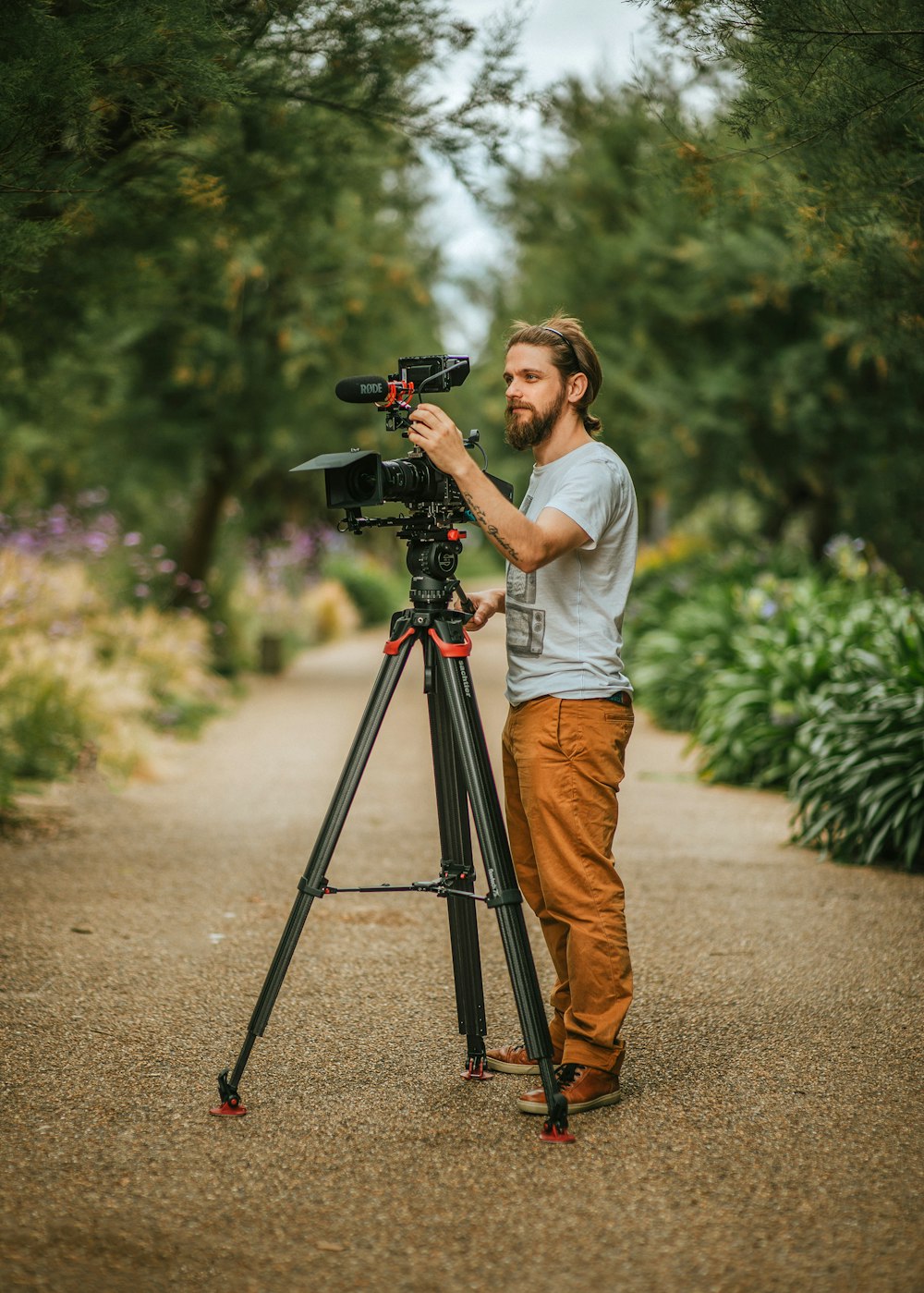 woman in white shirt and orange pants holding black dslr camera on tripod