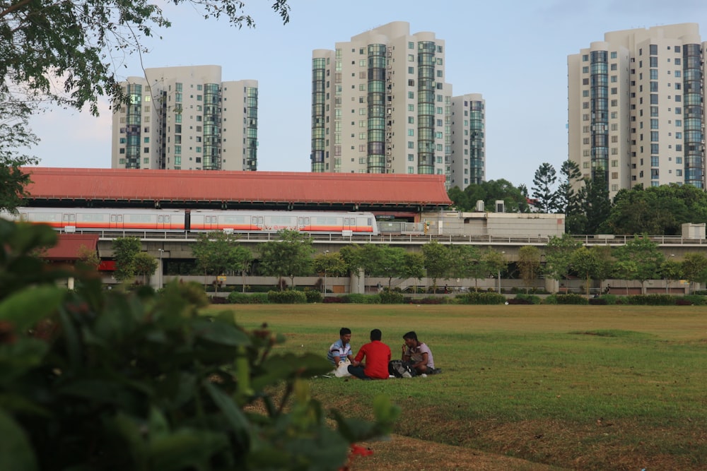 people sitting on green grass field near city buildings during daytime