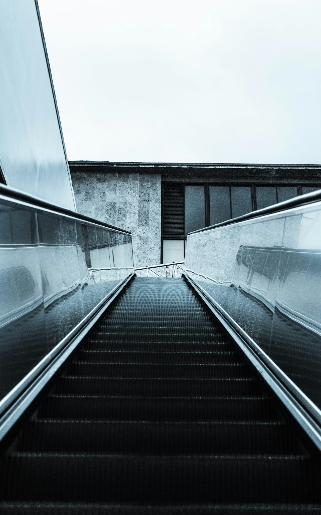 black escalator in between gray concrete building