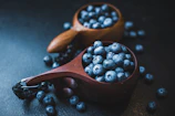 Close-up of fresh blueberries and wellness products on a wooden table with natural light