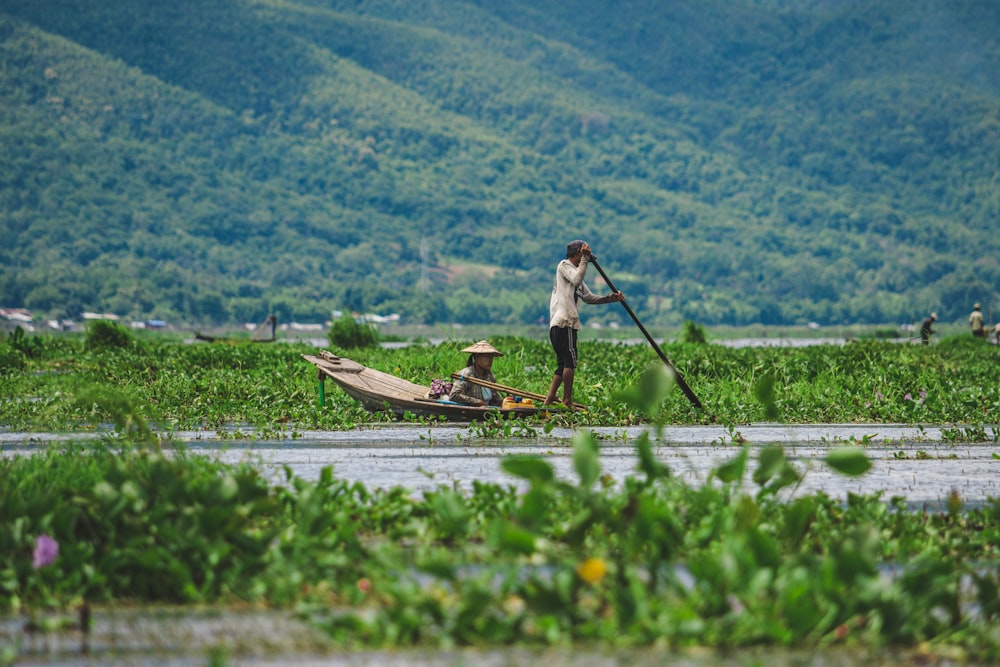 man in white shirt and black pants riding on brown boat on green grass field during