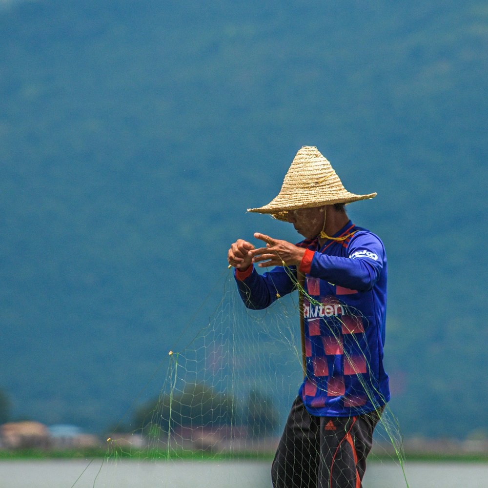 woman in blue and red dress wearing brown woven hat standing on green grass field during