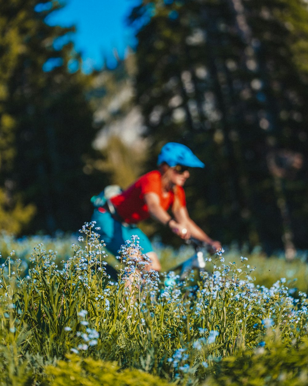 Person in rotem Hemd und blauem Hut, die tagsüber auf grünem Rasen läuft