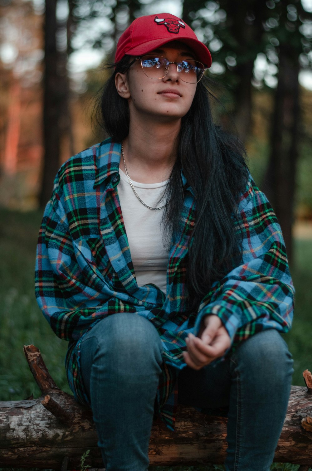 woman in red and black plaid dress shirt and blue denim jeans sitting on brown wooden