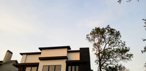 A sleek, modern home crowned with a deep royal purple and matte black premium roofing system under a clear sky.