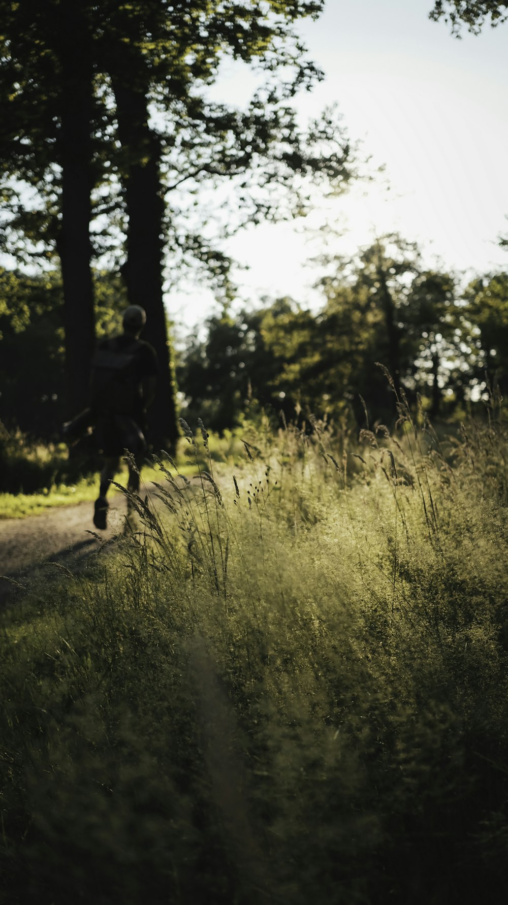 man in black jacket walking on green grass field during daytime