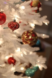 A snowy white Christmas tree glowing warmly in a softly lit corner with elegant ornaments.