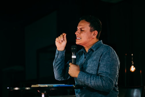 man in blue denim jacket holding microphone