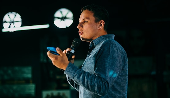 man in blue denim jacket holding microphone