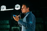 man in blue denim jacket holding microphone