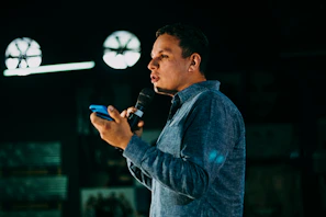 man in blue denim jacket holding microphone