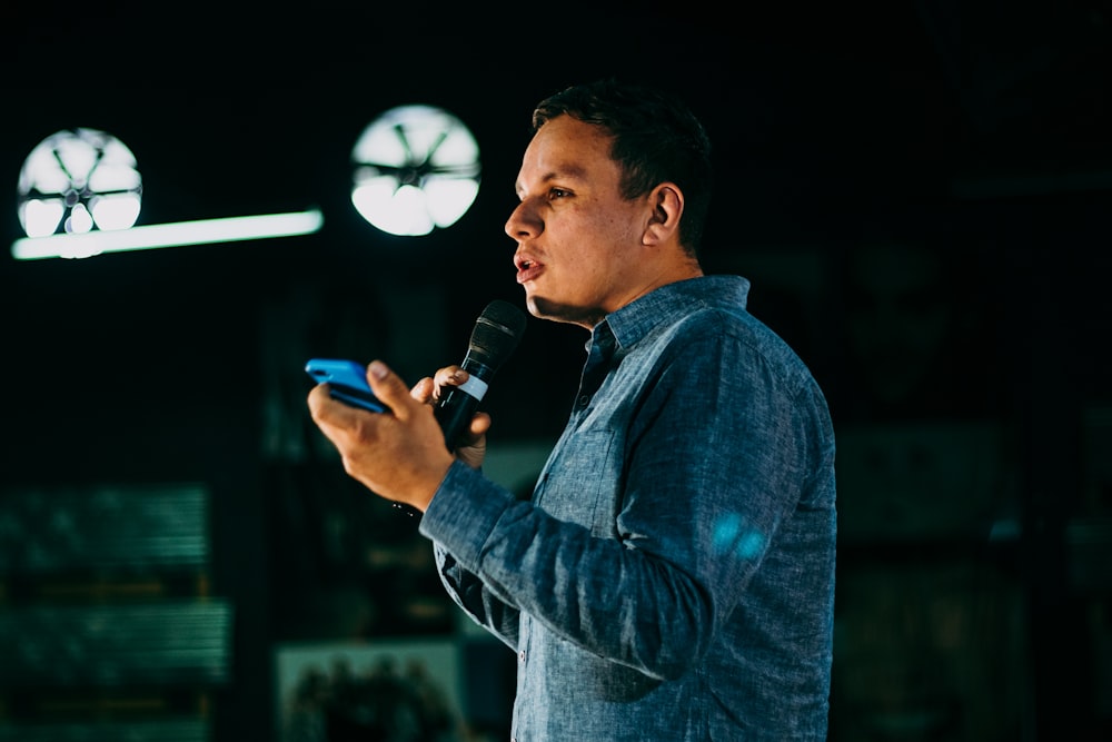 man in blue denim jacket holding microphone