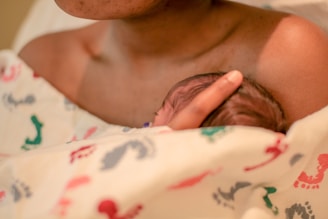 woman holding newborn baby under blanket