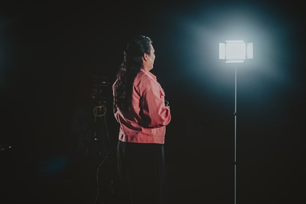 a woman standing in front of a light in the dark