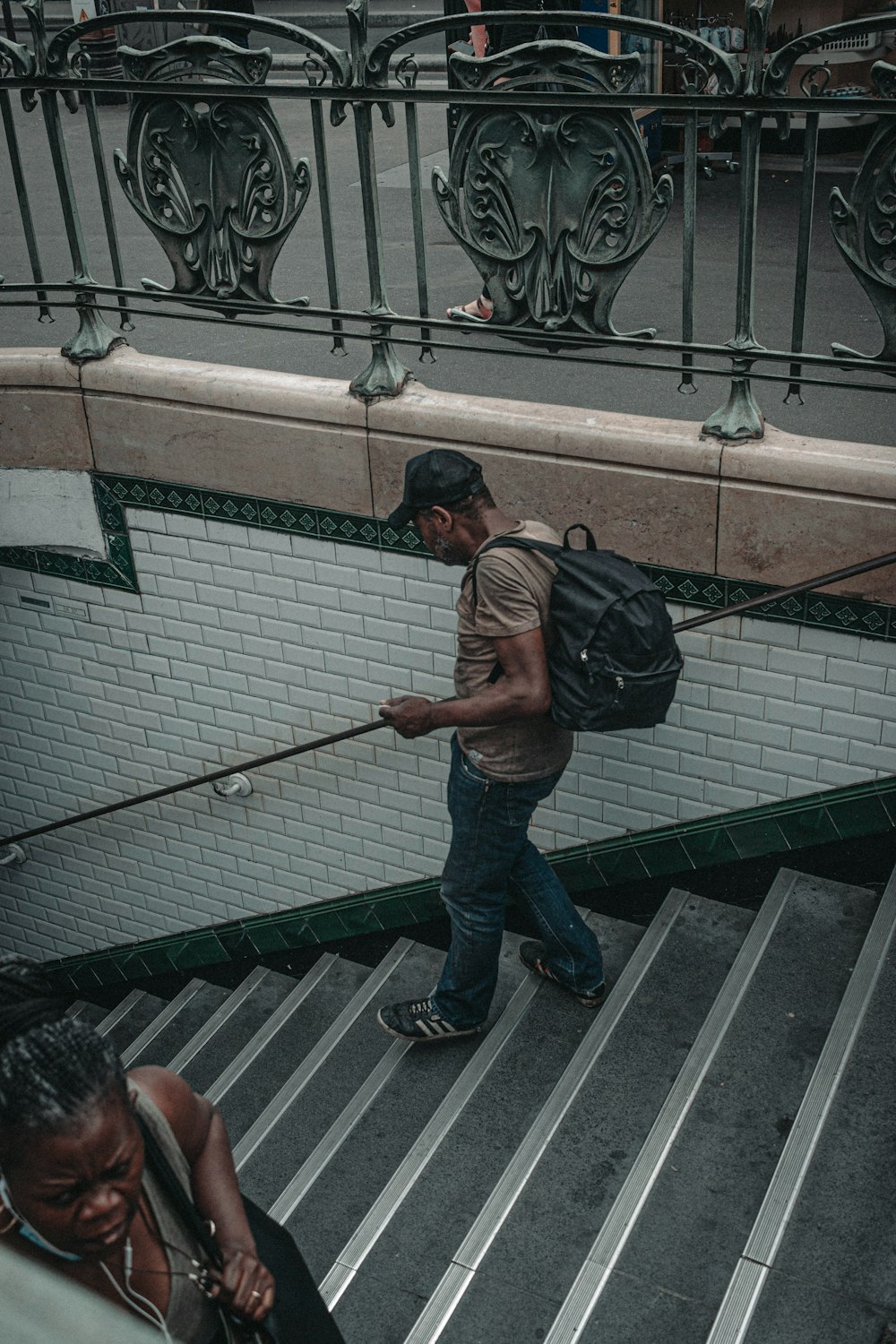 갈색 티셔츠와 파란색 데님 청바지를 입은 남자가 흑백 콘크리트 계단에 서 있다
