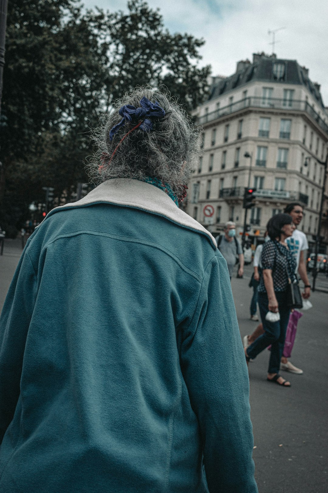 woman in blue coat walking on sidewalk during daytime