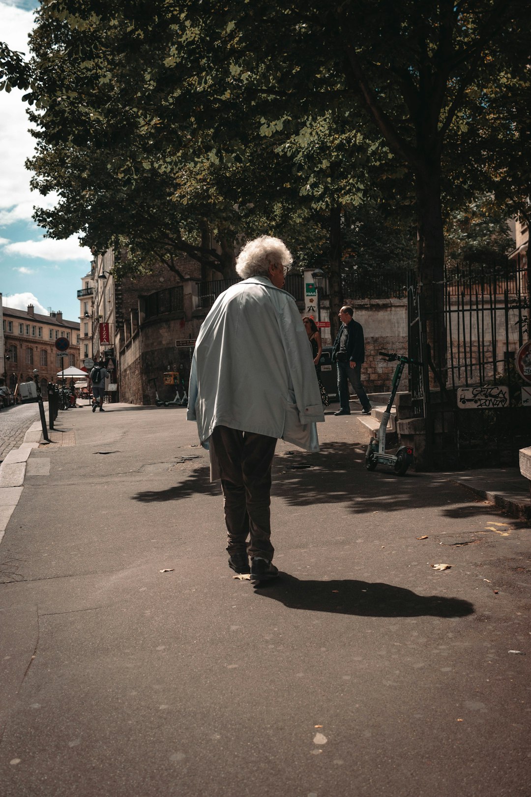 woman in white coat walking on sidewalk during daytime