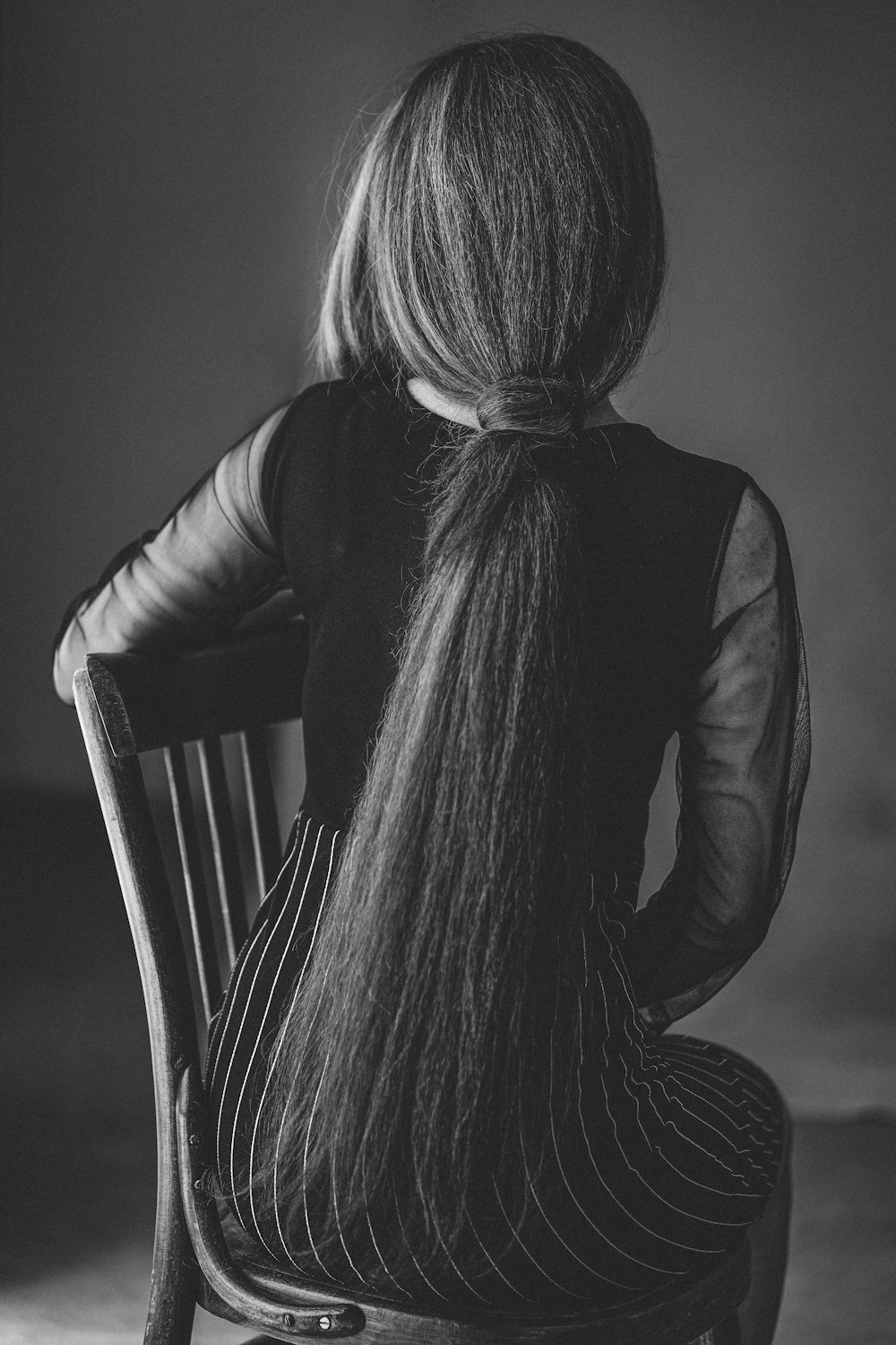 woman in black long sleeve shirt sitting on brown wooden chair