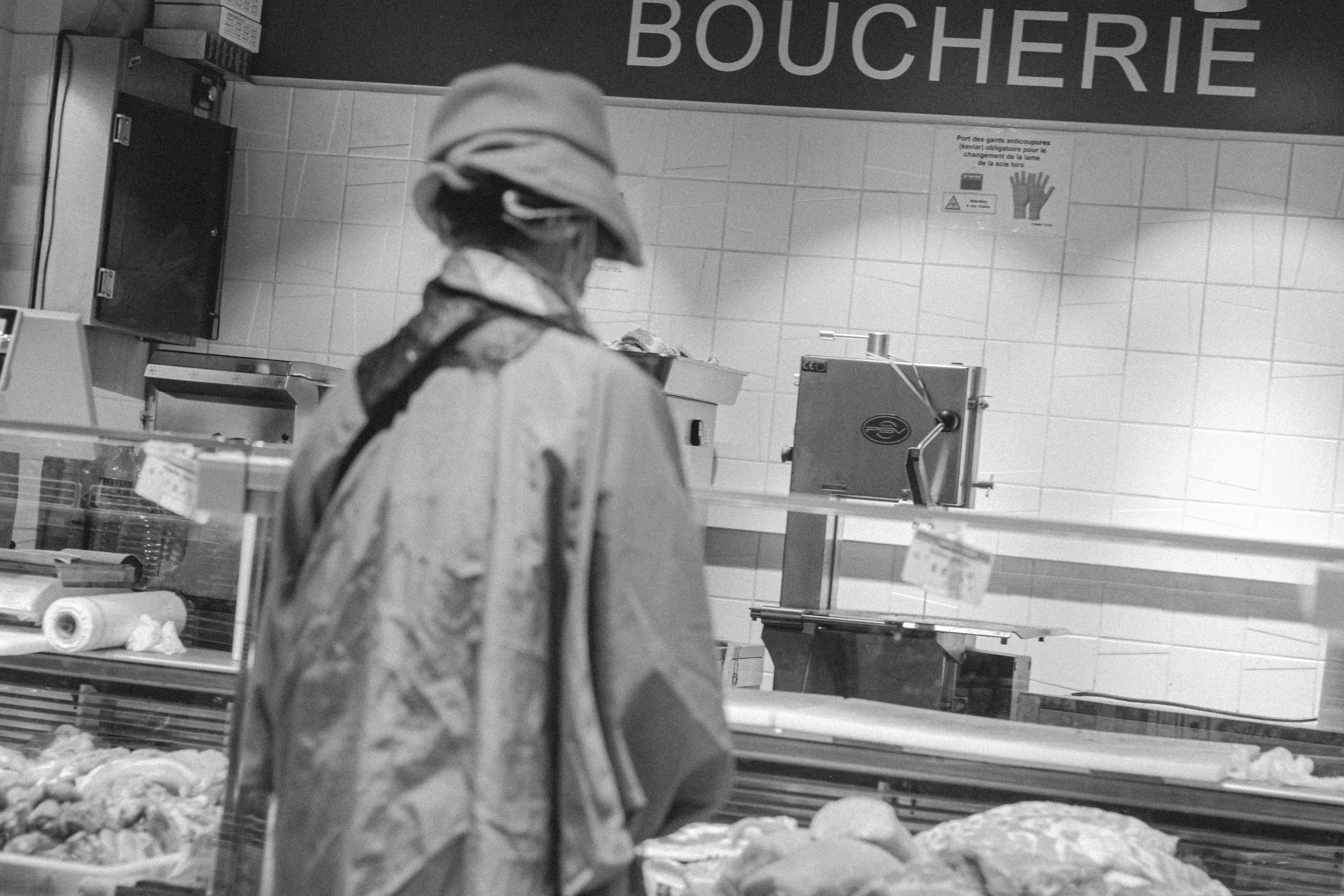 grayscale photo of person in hoodie standing in front of food display counter