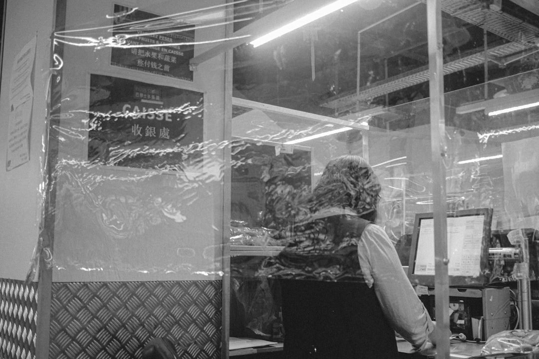 grayscale photo of man in white long sleeve shirt and pants standing in front of store