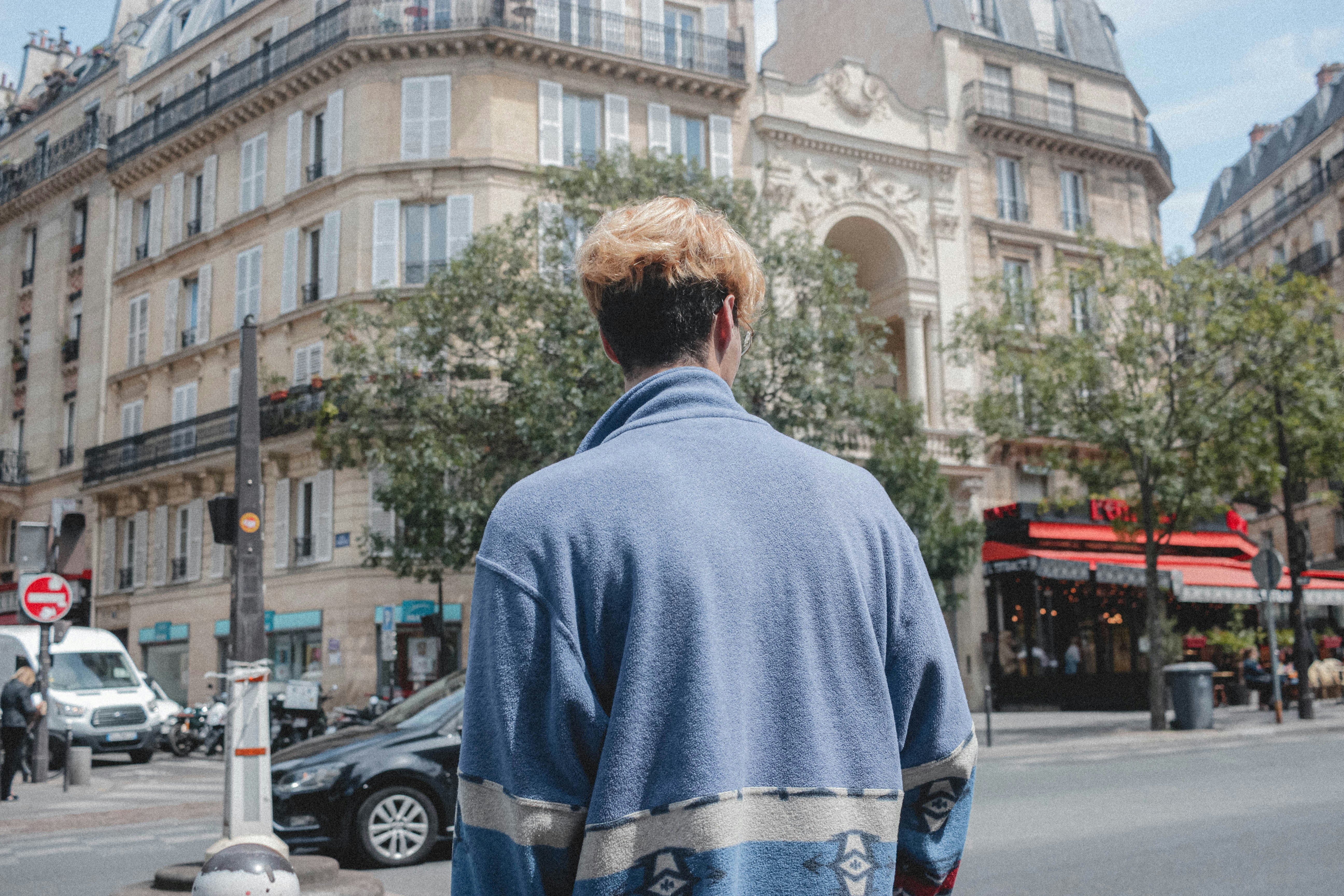 man in blue and white floral long sleeve shirt standing on road during daytime