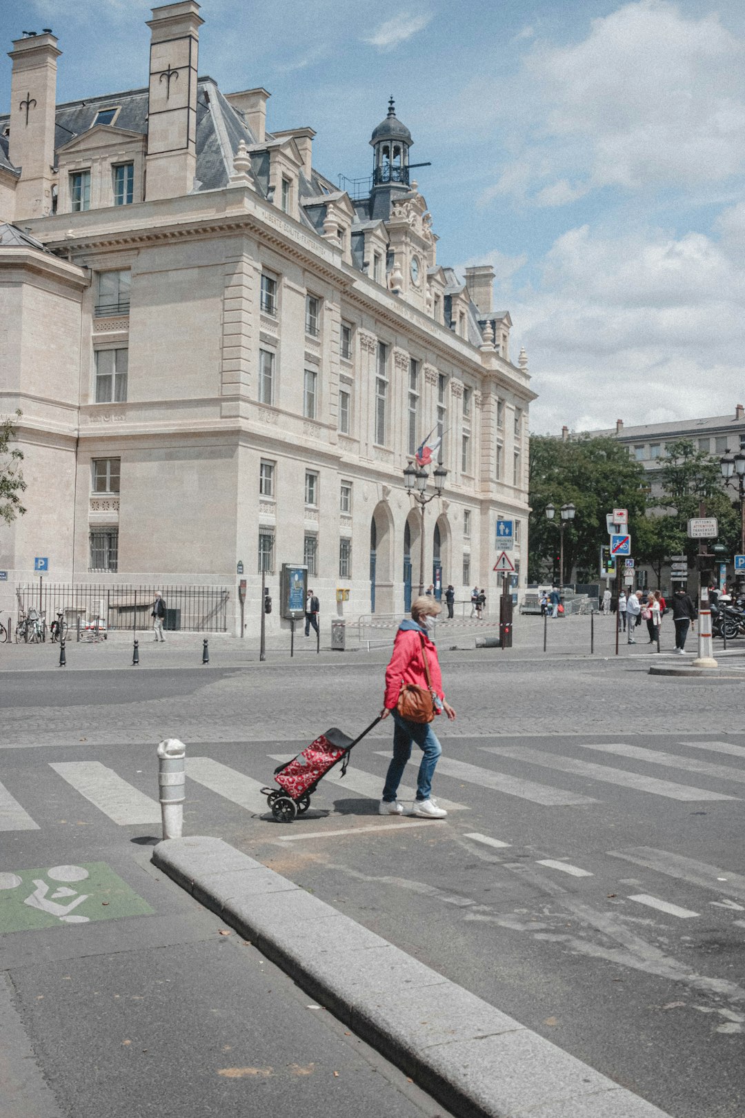 woman in red jacket and black pants walking on pedestrian lane during daytime