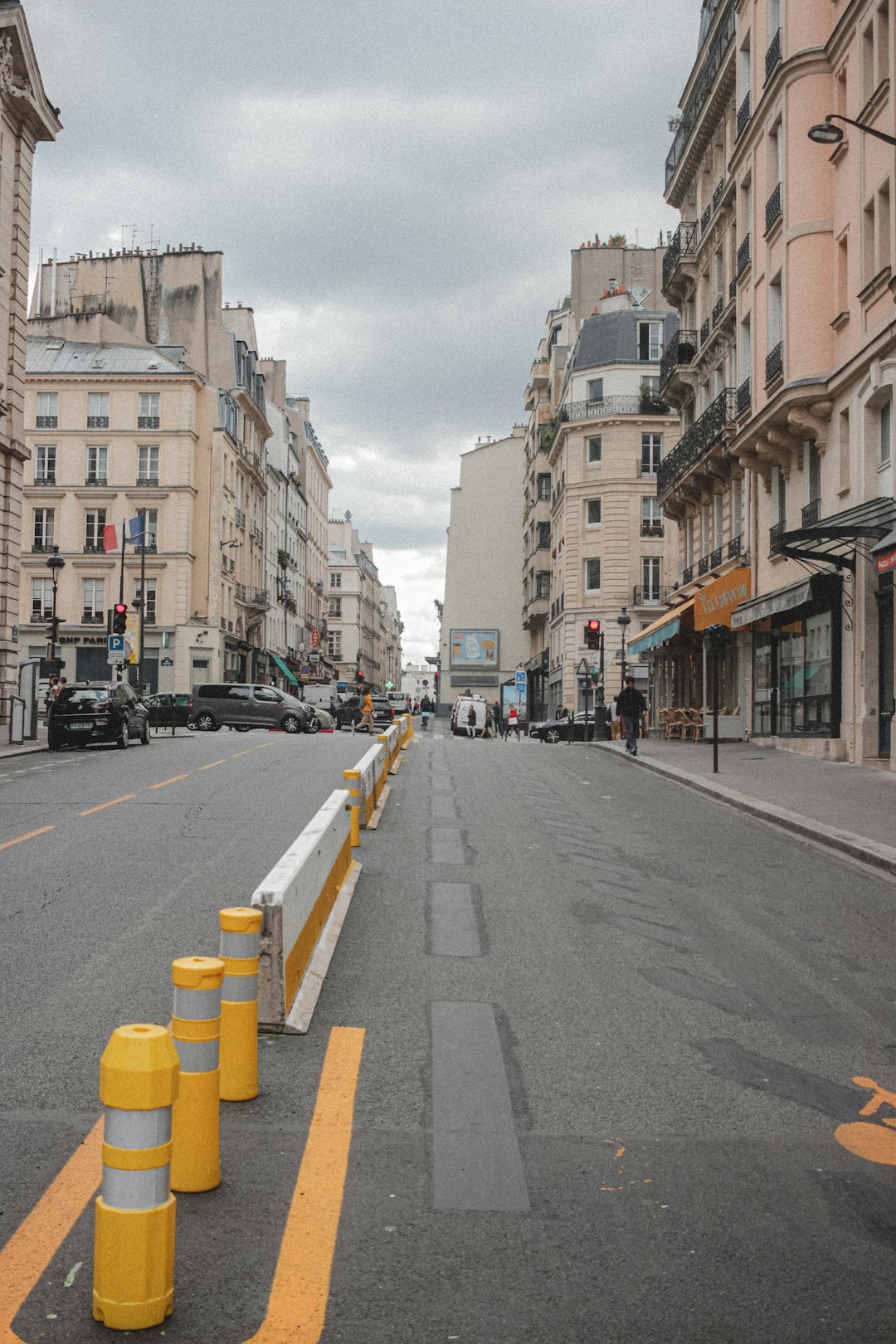 cars parked on side of the road in between high rise buildings during daytime