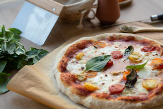 Ingredients laid out: ripe tomatoes, fresh basil, mozzarella, and dough ready to be made into pizza.
