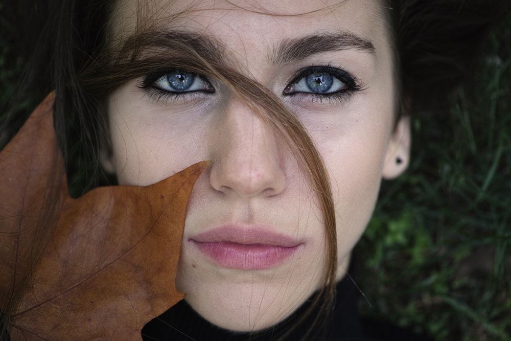 woman in black shirt with 
brown leaf on her face