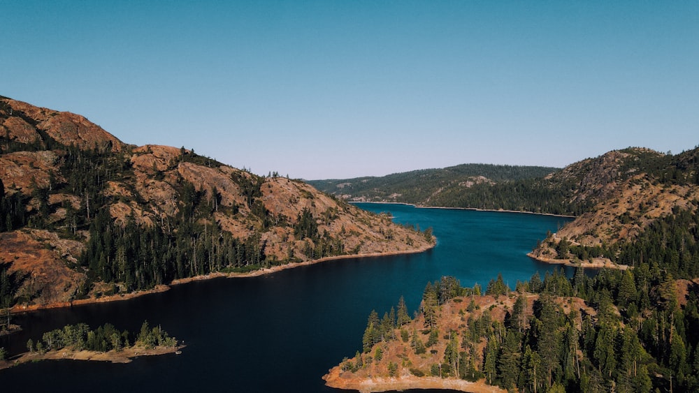 lake surrounded by trees and mountains during daytime