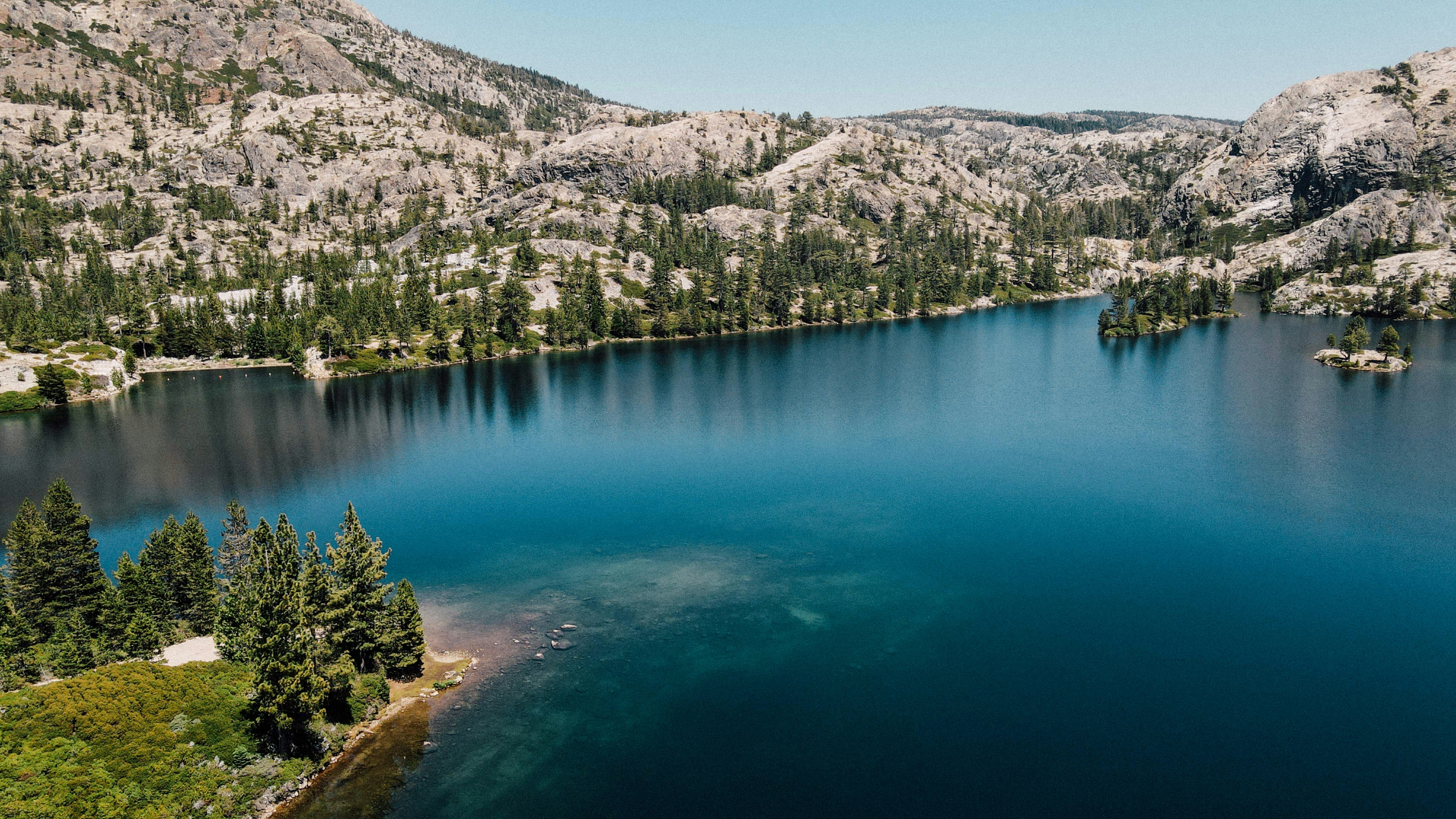 lake surrounded by green trees and mountains during daytime