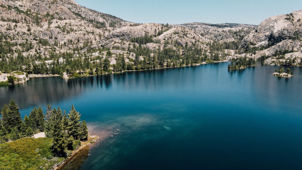 lake surrounded by green trees and mountains during daytime