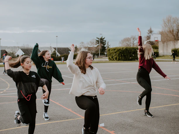 A group of diverse young people smiling and engaged in a community sports activity outdoors.