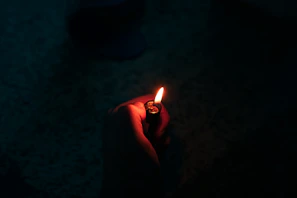 person holding lighted cigarette stick