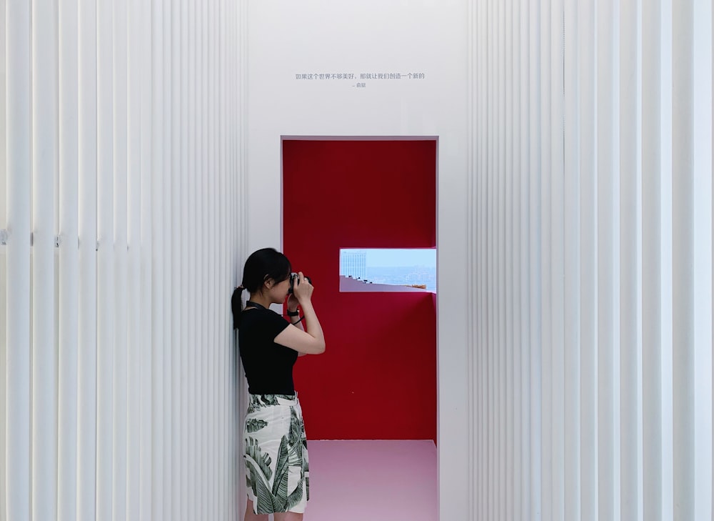 woman in black and white floral dress standing beside white wall