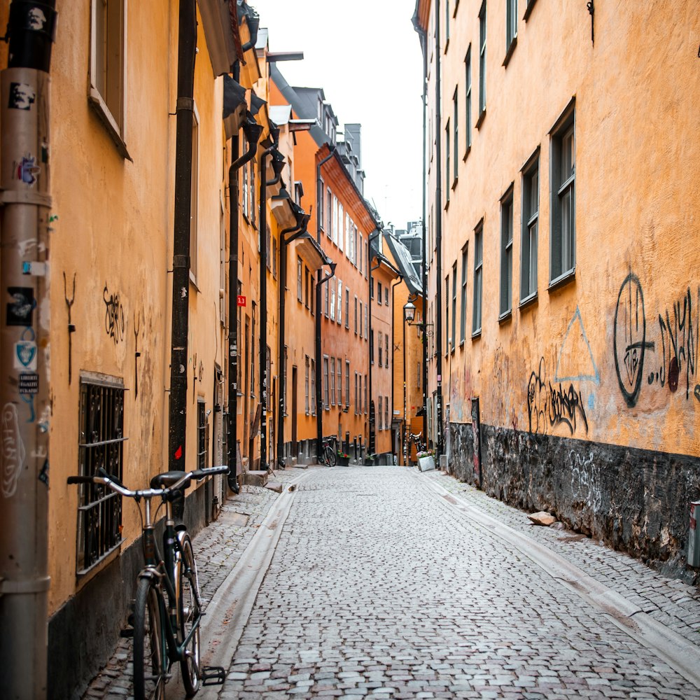 black bicycle parked on sidewalk between brown concrete buildings during daytime