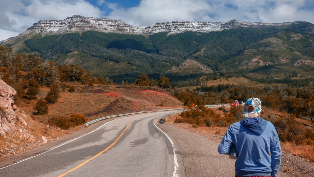 man in blue jacket walking on gray asphalt road during daytime