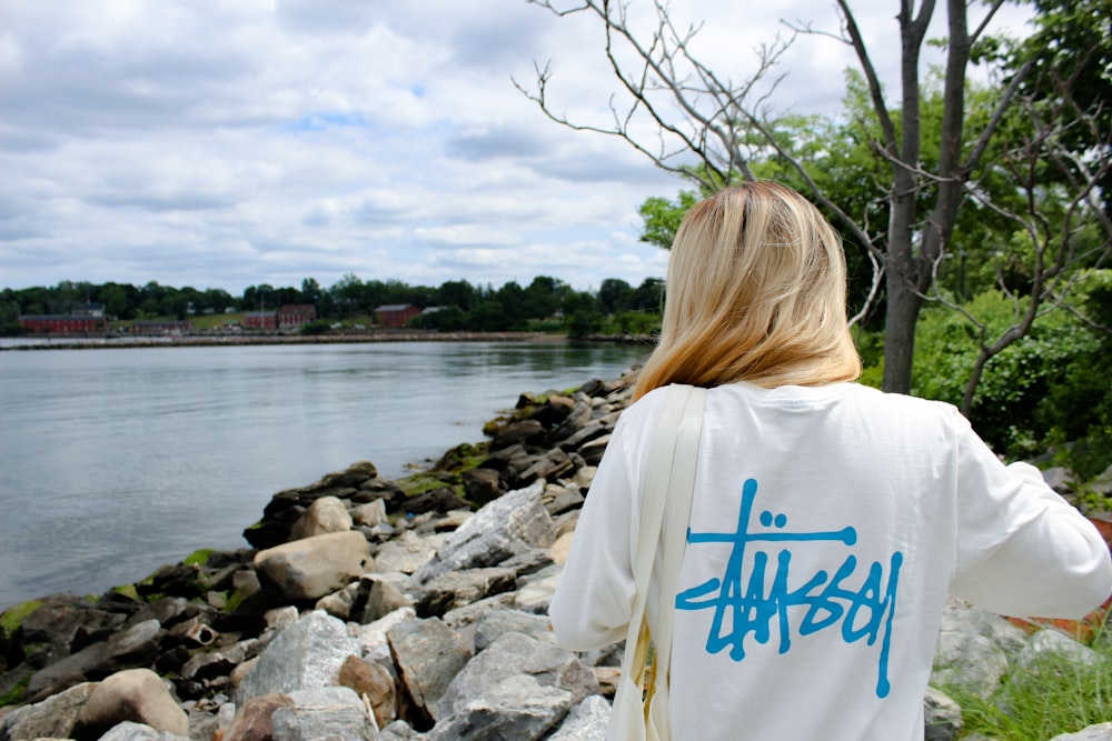 Frau im weiß-blauen Hemd tagsüber am felsigen Ufer