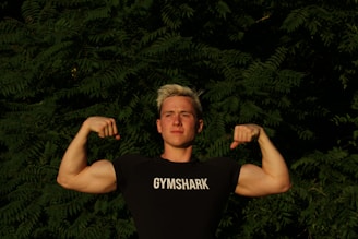 man in black tank top standing near green leaves