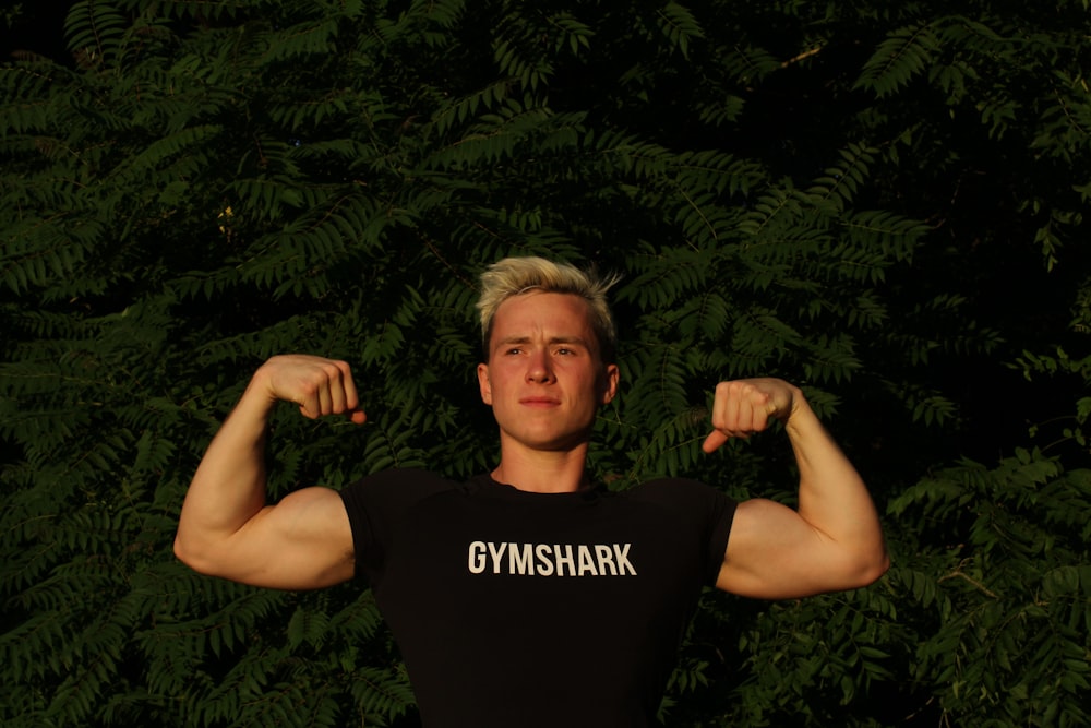 man in black tank top standing near green leaves