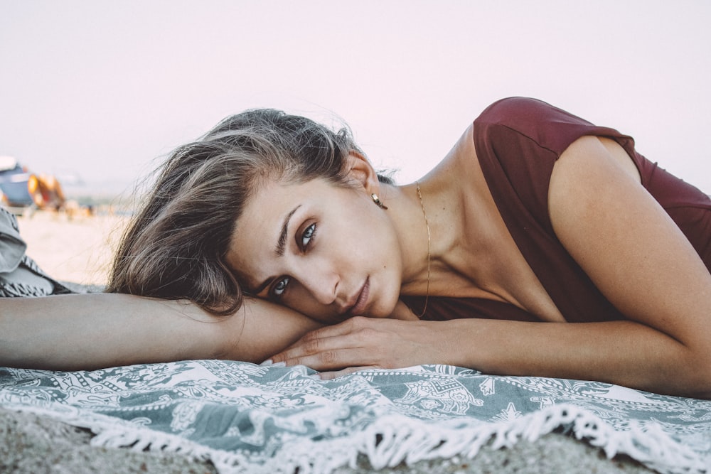 woman in maroon tank top lying on bed