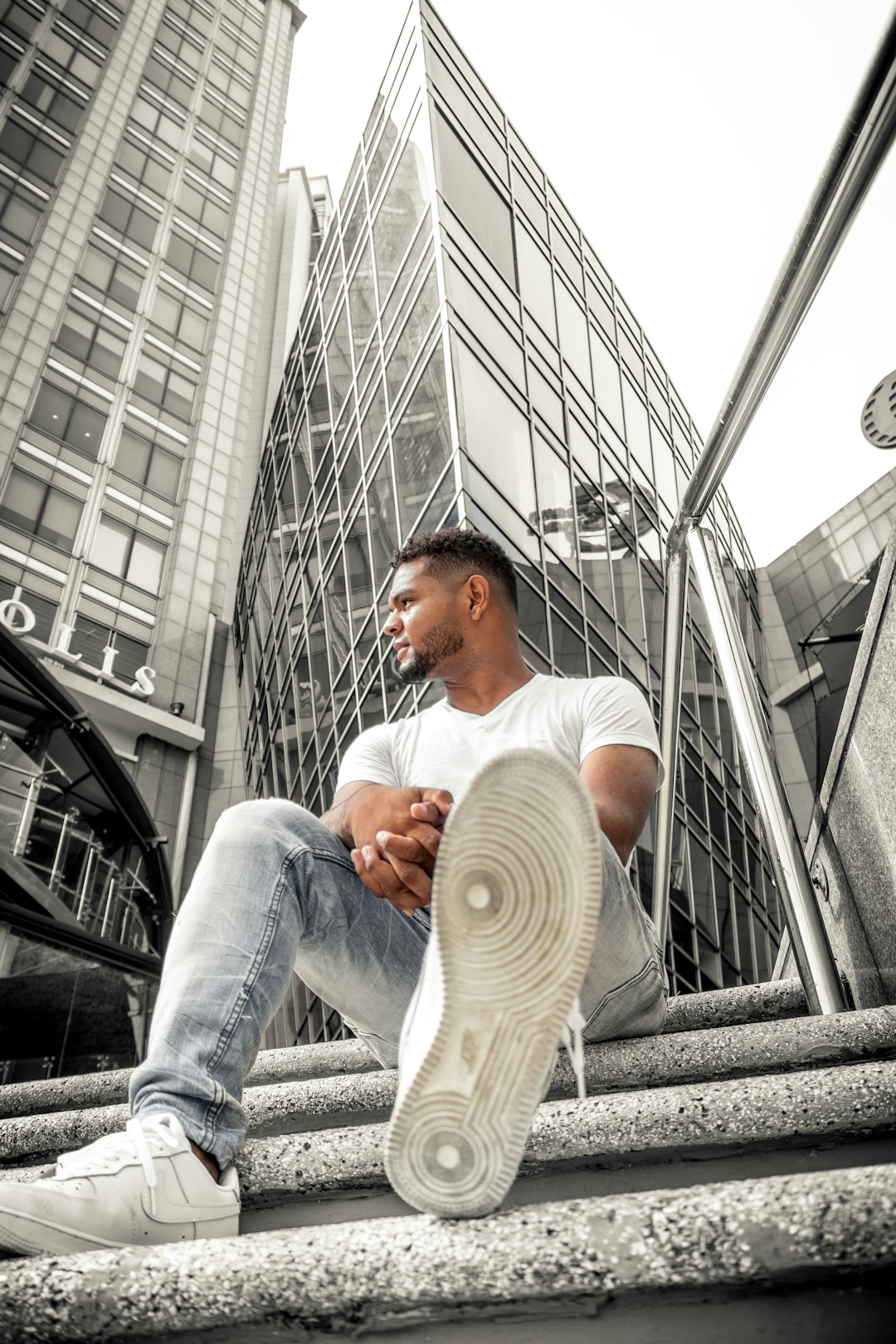 man in white t-shirt and blue denim jeans sitting on stairs