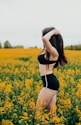woman in black and white bikini standing on yellow flower field during daytime