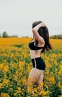 woman in black and white bikini standing on yellow flower field during daytime